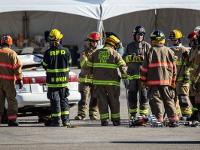 Firefighters in a group being instructed next to a broken down car