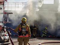 Firefighter carrying a firehose looking a smoking building