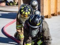 Firefighters kneeling down holding a firehose