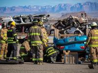 A group of firefighters looking at an overturned car