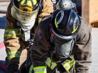 Firefighters kneeling down holding a firehose