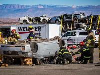 A group of firefighters looking at an overturned car