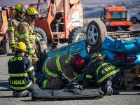 A group of firefighters looking at an overturned car