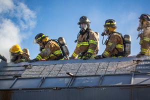 Firefighters standing on top of smoking building