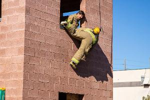 Firefighters helping each other out of a second story window