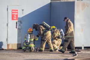 Firefighters kneeling next to a metal door