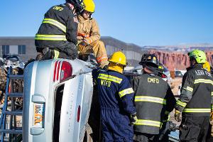 Group of firefighters next to a overturned car looking a mountain