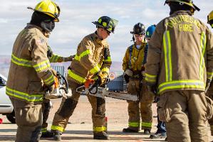 Firefighters cutting through plywood with a chainsaw