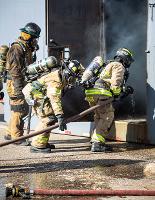 Firefighters looking into a metal door