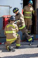 Firefighters prying open a red metal box with a crowbar