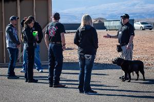 People gathered together listening to instruction from a man with a dog on a leash