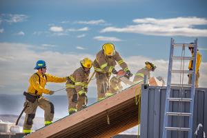 Firefighters cutting through plywood with a chainsaw