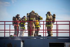 A group of firefighters standing on top of a building
