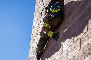 Firefighters helping each other out of a second story window