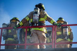 Firefighters standing on top of smoking building