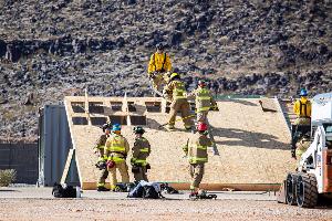 Firefighters climbing over a wooden structure