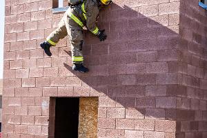 Firefighters helping each other out of a second story window