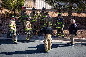 Firefighters gathered around listening to instruction from another firefighter