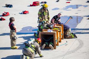 Firefighters crawling through a wooden tunnel.