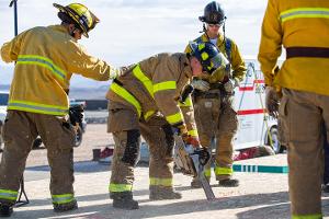 Firefighters cutting through plywood with a chainsaw