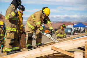 Firefighters cutting through plywood with a chainsaw