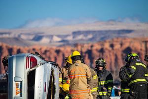 Group of firefighters next to a overturned car looking a mountain