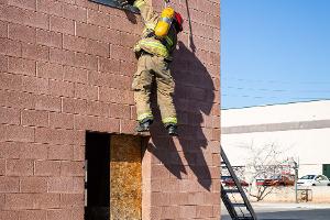 Firefighters helping each other out of a second story window