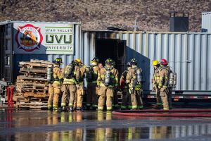 Firefighters gathered around a building listening to instruction.