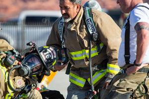 Firefighters sitting on the ground next to a firehose.