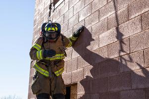 Firefighters helping each other out of a second story window