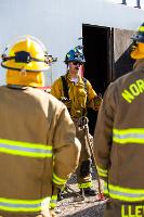 Firefighters prying open a red metal box with a crowbar