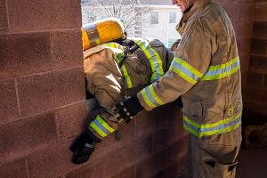 Firefighters helping each other out of a second story window