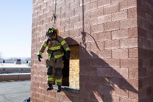 Firefighters helping each other out of a second story window