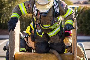 Firefighter climbing over a wooden obstacle