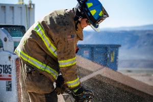 A firefighter cutting plywood with a saw