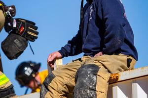 A firefighting instructor supervising sitting on a metal wall