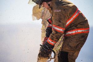 A firefighter cutting plywood with a saw