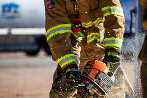 A firefighter cutting plywood with a saw