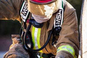 Firefighter climbing over a wooden obstacle