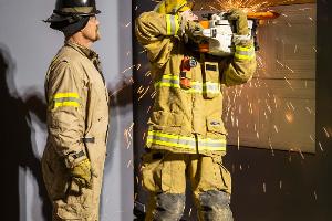 Two firefighters cutting a metal wall with a saw
