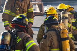 Supervising firefighter talking with kneeling firefighters