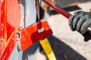 A firefighter prying open a container on the wall with a crowbar