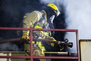 Firefighter with a house approaching smoke