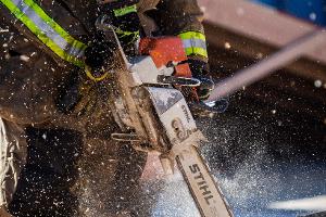 A firefighter cutting plywood with a saw