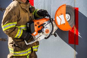 A firefighter cutting a metal wall with a saw