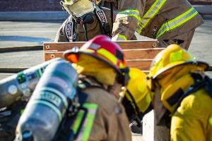 A supervising Firefighter watching over three firefighters training