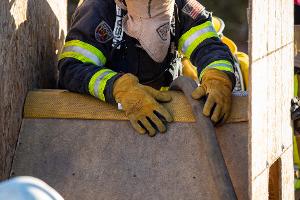 Firefighter climbing over a wooden obstacle