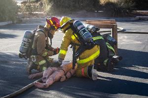 Two firefighters checking a training dummy for burns
