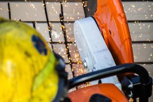 A firefighter cutting a brick wall with a saw