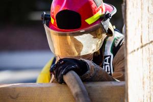 Firefighter climbing over a wooden obstacle